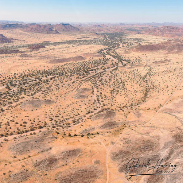 Aerial view of dry valleys, scattered vegetation and rugged desert plains in Damaraland, Namibia